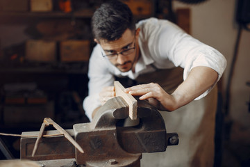 Man working with a wood. Carpenter in a white shirt