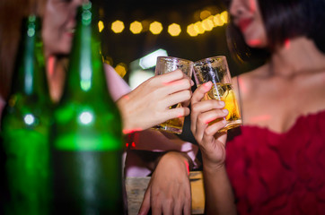 People at the party cheering together, have a drink of yellow fermented, frothy.  A