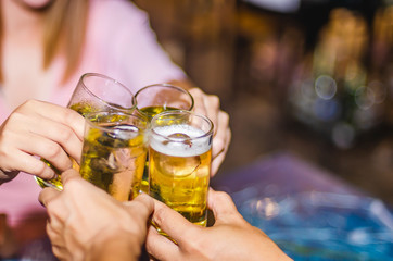 People at the party cheering together, have a drink of yellow fermented, frothy.  A