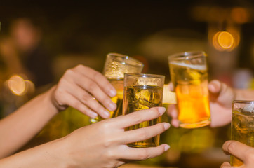 People at the party cheering together, have a drink of yellow fermented, frothy.  A