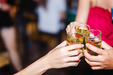 People at the party cheering together, have a drink of yellow fermented, frothy.  A