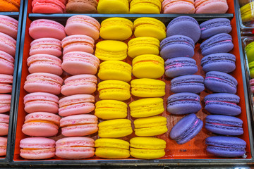 Pile of colorful macaroon cakes in tray at patisserie 