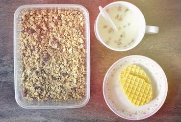 Square box Two slices of cookies on a small plate A glass of milk has floating cereals. Brown wooden table top Breakfast at the resort