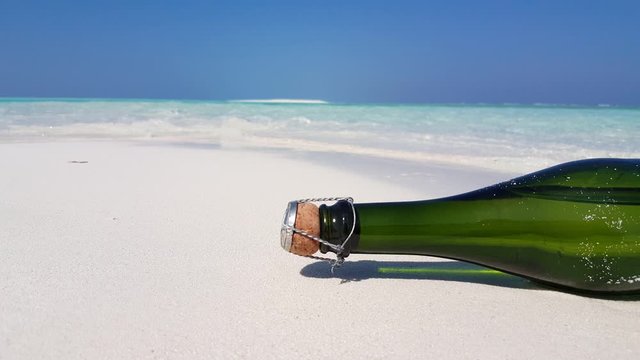 Concept design for a champagne bottle crashed  on white fine sand of empty beach in blur oceanic background