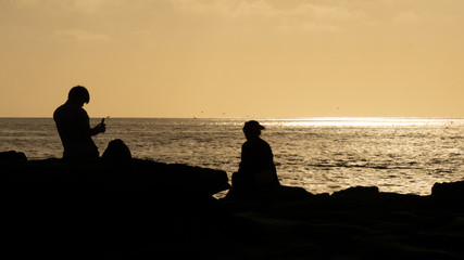 silhouettes of a couple at the beach watching sunset