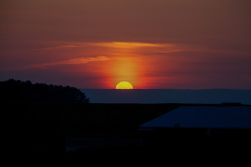 Fototapeta na wymiar Half sun over horizon with farm