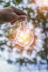hand holding light bulb against nature, icons energy sources for renewable 