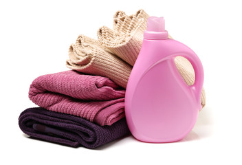 plastic bottle of detergent and a pile of clean laundry on a white background. Conditioner for linen