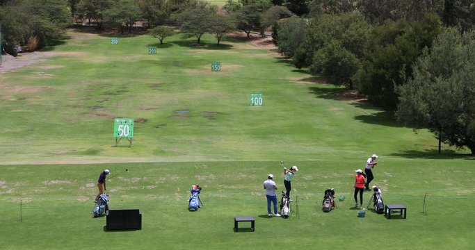 People practicing the golf swing at a golf range