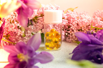 a jar with fish oil capsules and purple liliac flowers