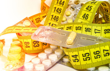 Pills with measuring tape, represent the diet pill industry. Diet meds concept