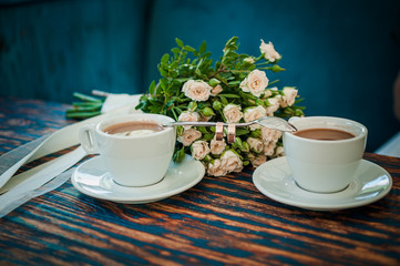 Pair of gold wedding rings on a spoon between two cups of coffee