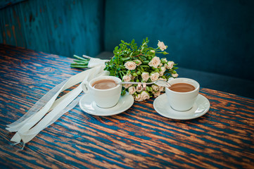Pair of gold wedding rings on a spoon between two cups of coffee