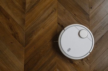 Robotic vacuum cleaner on laminate wood floor in bedroom