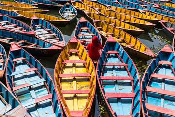 colorful boats in Fewa lake in Pokhara, Nepal with women in red sitting inside