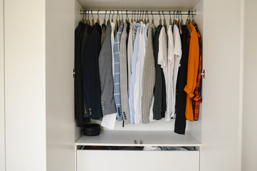 Many man's clothes in wardrobe, closeup. White wardrobe