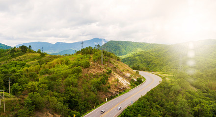 Aerial Landscape of Roads, travel routes in natural tourism in Thailand, paths cut through beautiful mountain forests And with the sky and sunshine as the background.