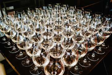 Glass of white wine on a table. Many glass wine in a row on bar counter. Shallow depth of field. Glasses with wine. Filled with half and stand on the holiday table. Furshet.
