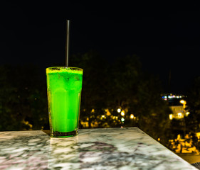delicious green cocktail on a marble table at night.