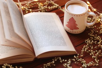 Christmas cup of tea with a Christmas tree ,Book with open pages,Vintage garland on a red wooden background. Books about Christmas. Winter Tea.