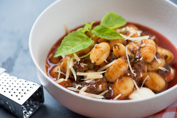 Closeup of potato gnocchi with tomato sauce, spinach, mozzarella and parmesan cheese, selective focus