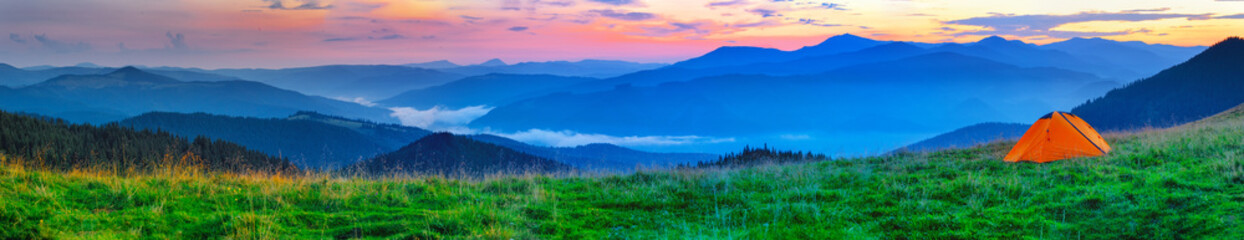 Orange tent on plain in the mountains