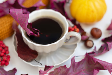 Autumn coffee time. Autumn leaves, pumpkins and berries on white table. 