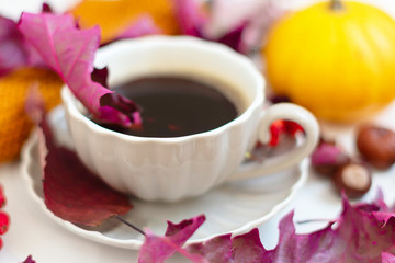 Autumn coffee time. Autumn leaves, pumpkins and berries on white table. 