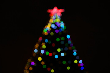 Christmas tree light on black background. blurry bokeh tree lights, Red star on the top of the head