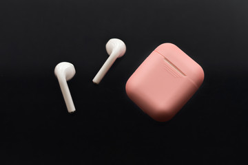 wireless headphones and pink case on dark background