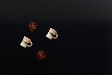 toy cups of coffee and cookies on a dark background. creative minimalist concept.