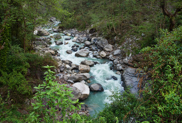 Beautiful landscape with a stormy mountain river of blue color in the jungle of Nepal, on a cloudy day