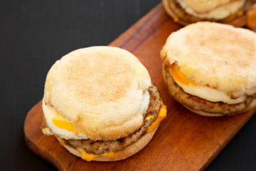 Tasty homemade pork roll egg sandwich on a rustic wooden board on a black background, side view. Close-up.