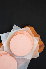 Sliced pork bolgna meat on a rustic wooden board on a black surface, top view. Flat lay, overhead, from above. Copy space.