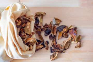 dried mushrooms in fabric bag on a wooden background