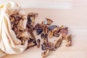 dried mushrooms in fabric bag on a wooden background