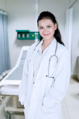 Confident female doctor standing in patient room