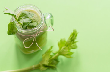 fresh celery juice in a jar on green background. concept of healthy food and detox