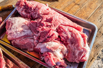 a large pot of freshly slaughtered pork ribs on a wooden chopping board