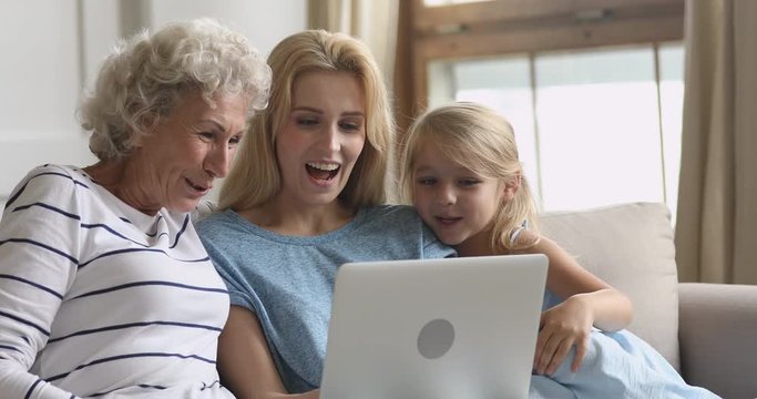 Happy three generation family using laptop watching funny cartoons