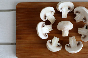 White mushrooms champignons on the wooden desk and grey background.