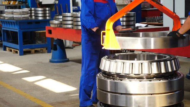 Massive bearing assembly. Close up. Worker lifts part of rolling bearing with hoister. Heavy machinery concept. Part of manufacture. Shot in 4k