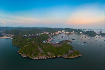 Aerial unique view Vietnam Cat Ba bay with floating fishing boats on sea, cloudscape tropical weather inspirational sunset, epic city skyline and skyscraper, scenic green mountain. © fabio lamanna