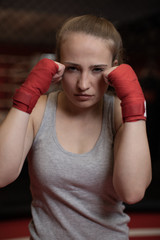 Boxing , wrestling , and MMA duel . Young strong girl kickboxer fighter stands in a defensive or...