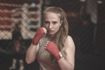 Boxing , wrestling , and MMA duel . Young strong girl kickboxer fighter stands in a defensive or...
