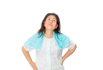 An Asian woman in blue pajamas is standing and looking up in studio with one small blue towel over her shoulder.