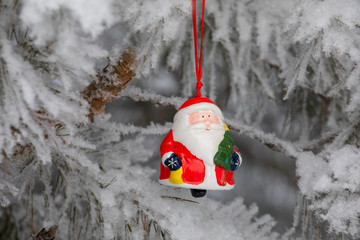 New Year. Christmas and decorations. Toy Santa Claus swinging on a branch in the forest. Snowing