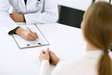 Woman doctor and patient sitting and talking at medical examination at hospital office, close-up....