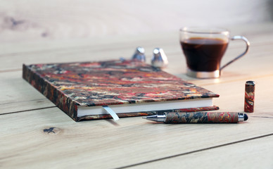 notebook on wooden  table with pen and coffee