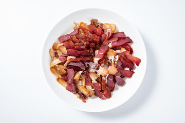 A plate of red Hunan Xiangxi smoked bacon slices on a white background